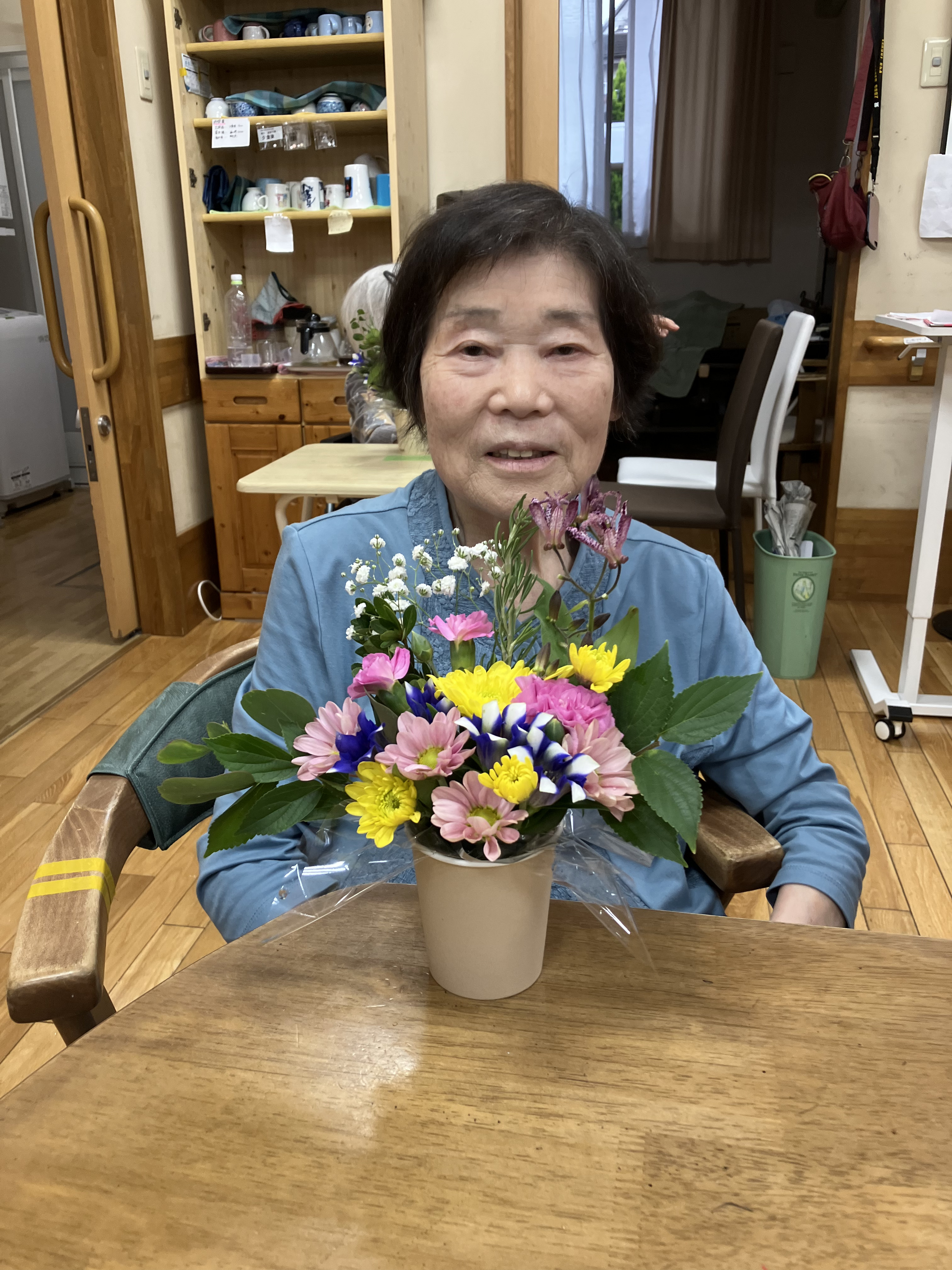 完成したフラワーアレンジメントと一緒にうつる利用者さん